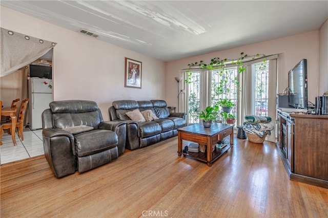 living room with visible vents and light wood-style flooring