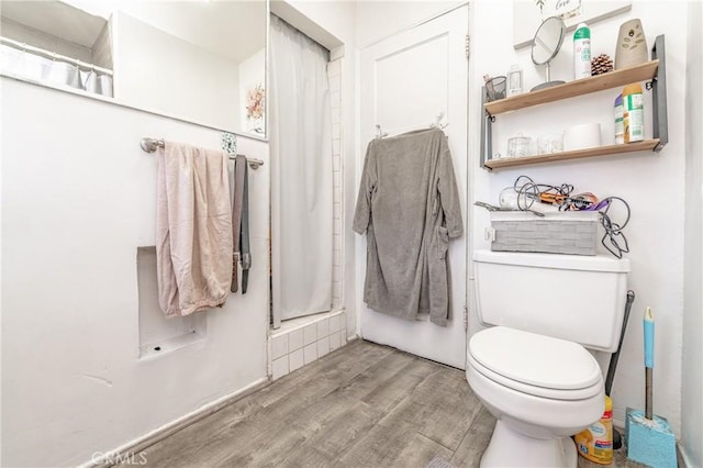 bathroom featuring a shower with shower curtain, toilet, and wood finished floors