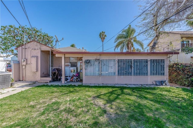 rear view of house featuring fence, a lawn, stucco siding, a sunroom, and a patio area