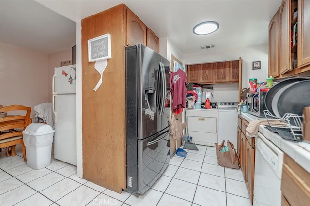 kitchen with visible vents, light tile patterned flooring, light countertops, appliances with stainless steel finishes, and brown cabinets