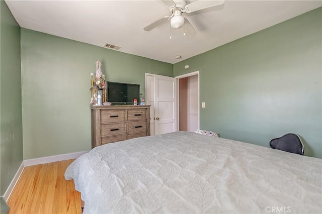 bedroom featuring ceiling fan, wood finished floors, visible vents, and baseboards