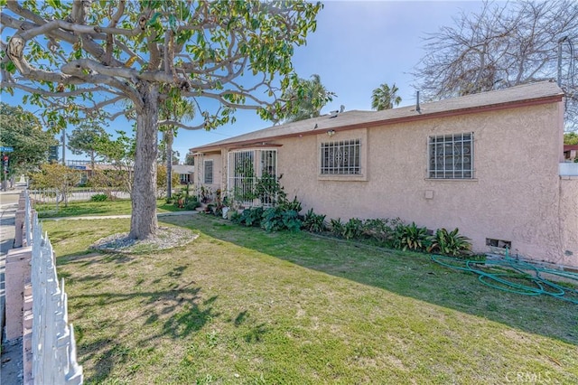 rear view of house featuring stucco siding and a yard