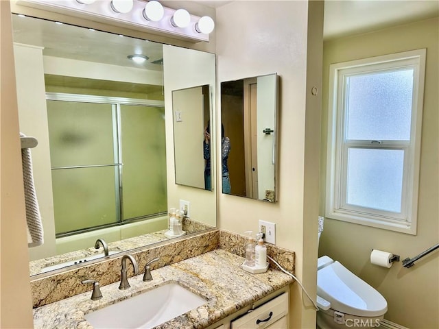 bathroom with toilet, vanity, and a shower with shower door