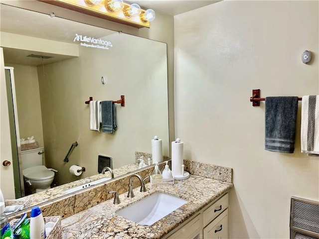 bathroom with heating unit, toilet, and vanity