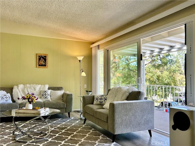 living area featuring vaulted ceiling, a textured ceiling, and wood finished floors