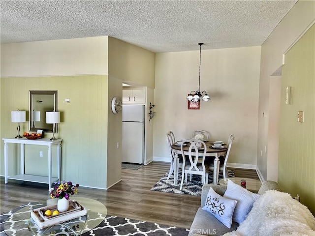 interior space featuring a textured ceiling, wood finished floors, baseboards, and a chandelier