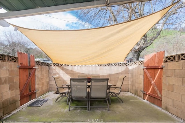 view of patio featuring outdoor dining area, fence, and a gate