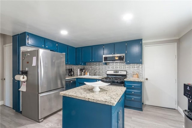 kitchen featuring a kitchen island, blue cabinetry, stainless steel appliances, decorative backsplash, and light wood-style floors