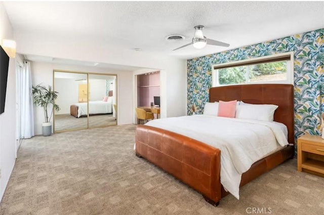 bedroom with visible vents, wallpapered walls, carpet flooring, a textured ceiling, and a ceiling fan