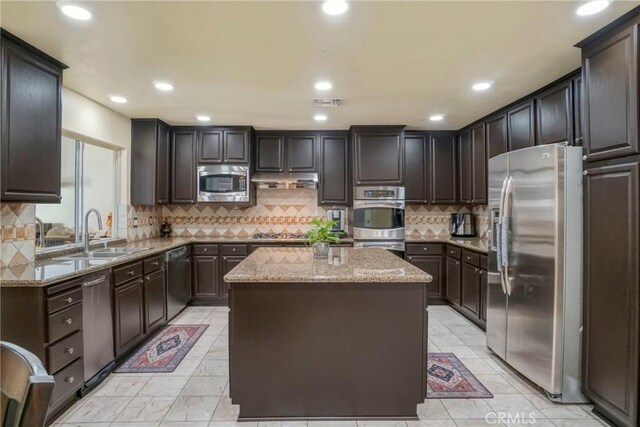 18429 Germain St, Porter Ranch, CA 91326 - kitchen with stainless steel appliances, a sink, a center island, light stone counters, and decorative backsplash