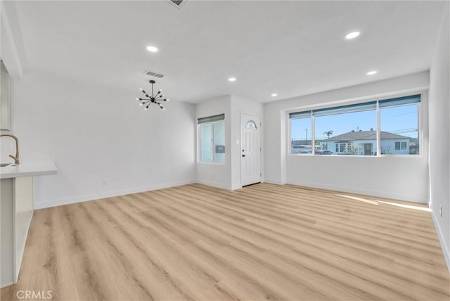 unfurnished living room featuring visible vents, baseboards, a chandelier, recessed lighting, and light wood-style floors