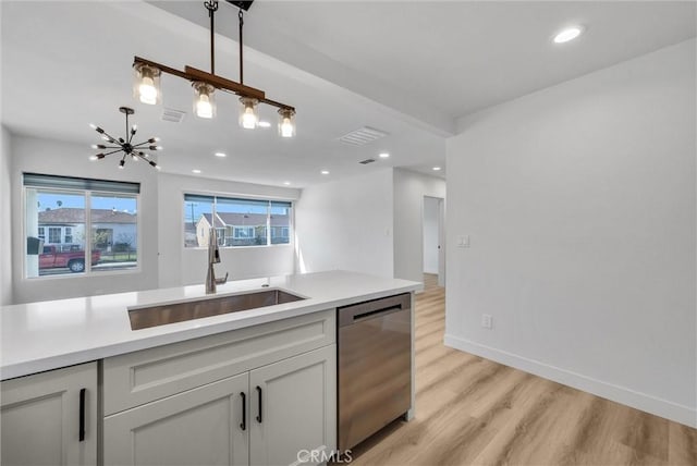 kitchen with light wood finished floors, visible vents, dishwasher, light countertops, and a sink