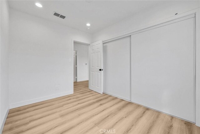 unfurnished bedroom with visible vents, wood finished floors, recessed lighting, a closet, and baseboards