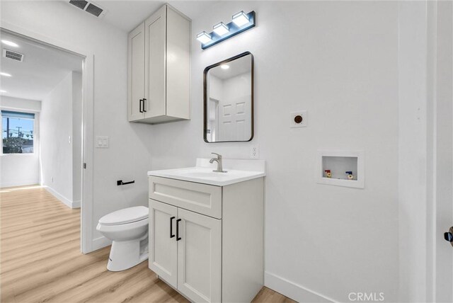 bathroom with visible vents, toilet, vanity, and wood finished floors