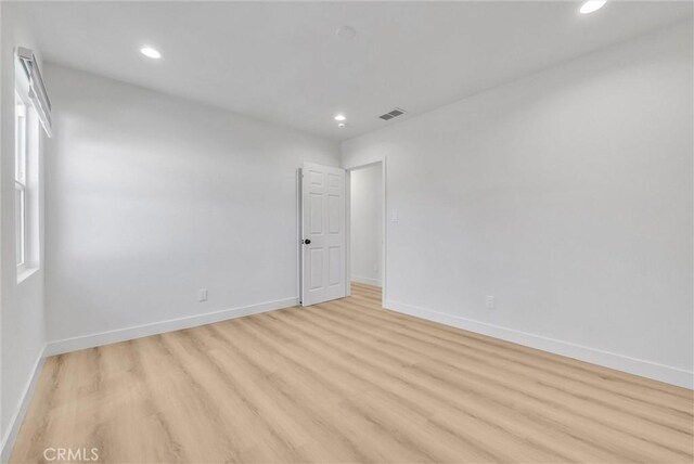 empty room with visible vents, recessed lighting, light wood-type flooring, and baseboards