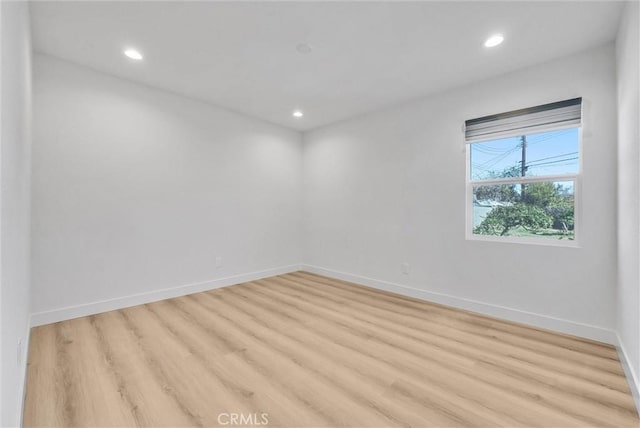 empty room featuring recessed lighting, baseboards, and light wood finished floors