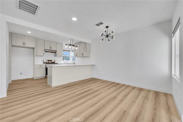 kitchen featuring under cabinet range hood, visible vents, stainless steel range oven, and a notable chandelier