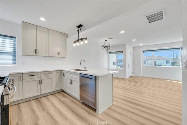 kitchen with light wood finished floors, visible vents, appliances with stainless steel finishes, a peninsula, and a sink