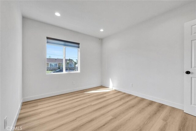 empty room featuring recessed lighting, baseboards, and wood finished floors