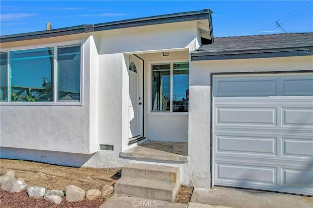 property entrance with visible vents, stucco siding, an attached garage, and roof with shingles