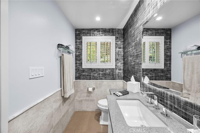 bathroom featuring toilet, tile walls, tile patterned flooring, and a healthy amount of sunlight