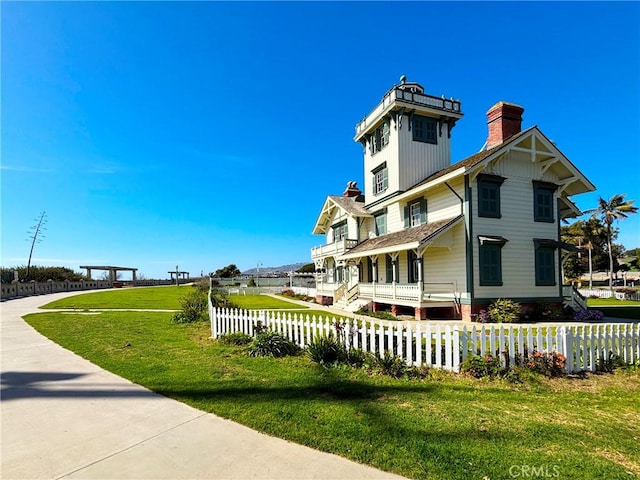 view of side of home featuring a fenced front yard, a lawn, and a chimney