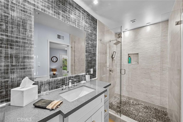 bathroom featuring visible vents, tile walls, a stall shower, and vanity