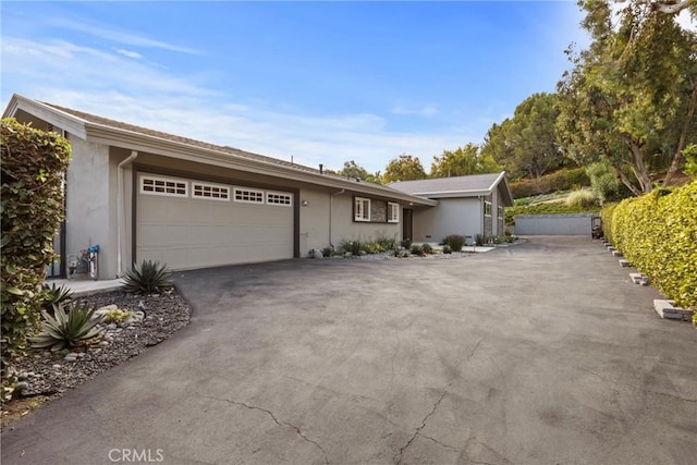 single story home with aphalt driveway, a garage, and stucco siding