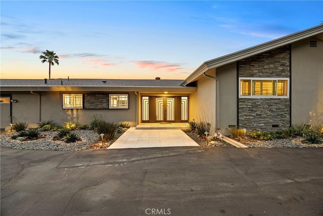 exterior entry at dusk with stone siding and stucco siding