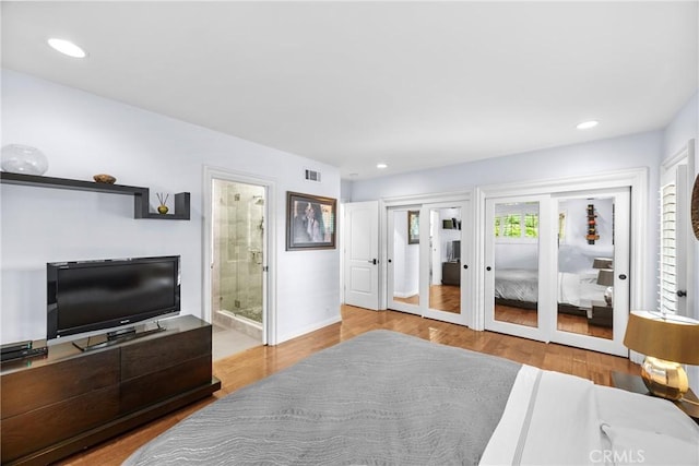 bedroom with wood finished floors, visible vents, ensuite bath, recessed lighting, and multiple closets