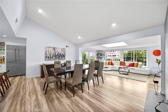 dining room featuring baseboards, high vaulted ceiling, a skylight, recessed lighting, and light wood-type flooring