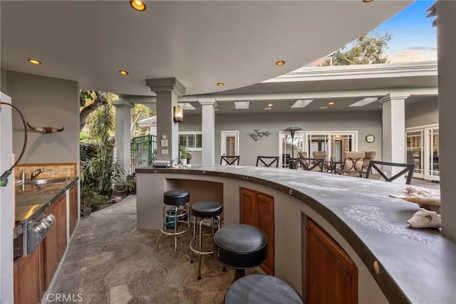 exterior space with a warming drawer, recessed lighting, ornate columns, and a sink