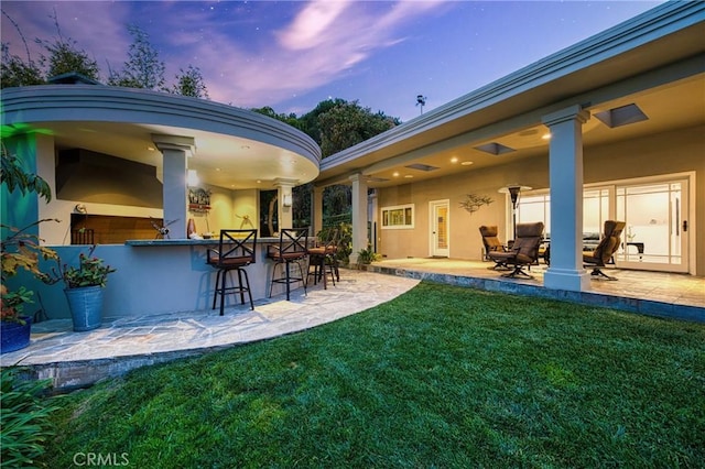 exterior space with a yard, a patio area, outdoor dry bar, and stucco siding