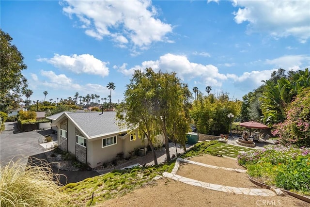 view of side of property featuring a patio area, roof with shingles, and stucco siding