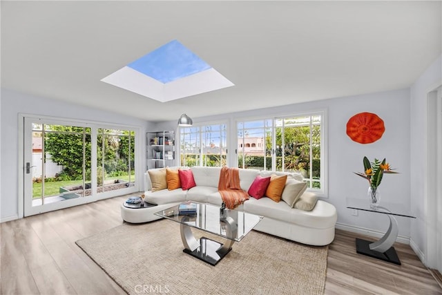 living room with baseboards, lofted ceiling with skylight, and wood finished floors