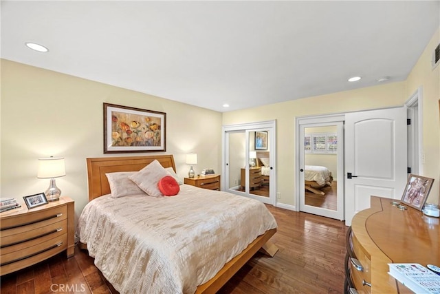 bedroom with dark wood finished floors, recessed lighting, baseboards, and multiple closets