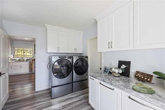 laundry area featuring cabinet space, independent washer and dryer, light wood-style floors, and a sink