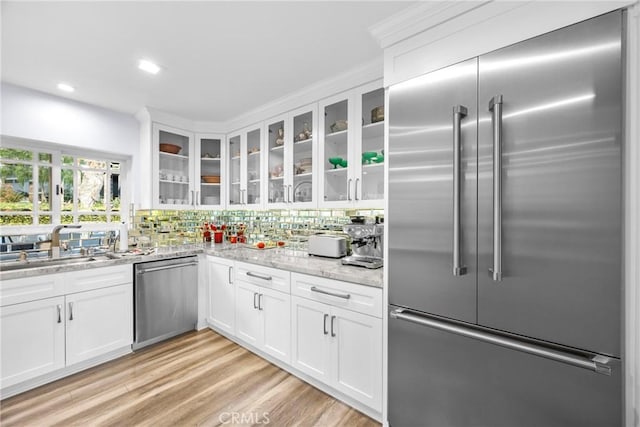 kitchen featuring light wood-style flooring, glass insert cabinets, appliances with stainless steel finishes, white cabinetry, and tasteful backsplash