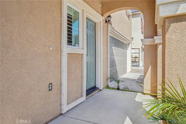 view of exterior entry with stucco siding and a garage