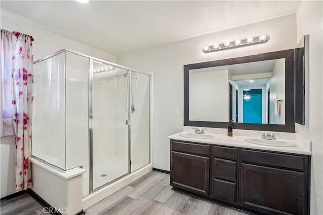 bathroom with a stall shower, wood finished floors, and a sink