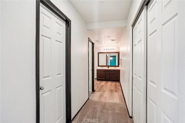 hall with a sink and light carpet