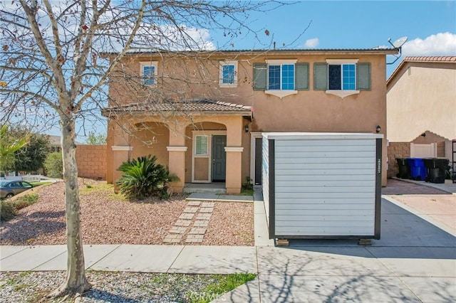 view of front of property featuring stucco siding, driveway, an attached garage, and fence