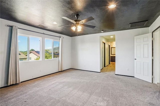 interior space featuring light carpet, visible vents, a textured ceiling, and baseboards