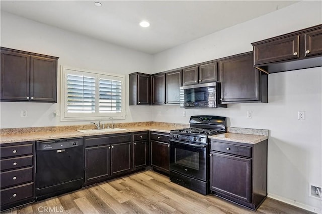 kitchen featuring a sink, light wood-style floors, black appliances, and dark brown cabinets