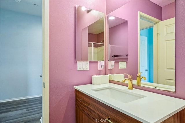 bathroom with a shower with shower door and vanity