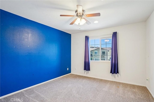 spare room featuring carpet flooring, a ceiling fan, and baseboards