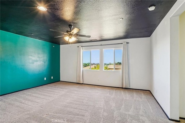 empty room featuring visible vents, carpet floors, a textured ceiling, and ceiling fan