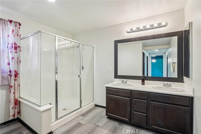 bathroom featuring a sink, wood finished floors, and a stall shower