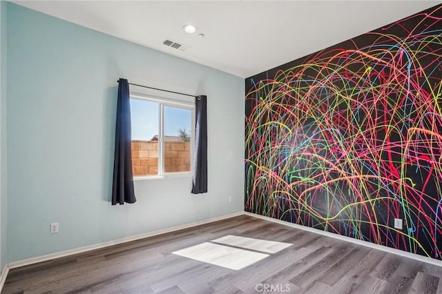 unfurnished room featuring recessed lighting, wood finished floors, visible vents, and baseboards