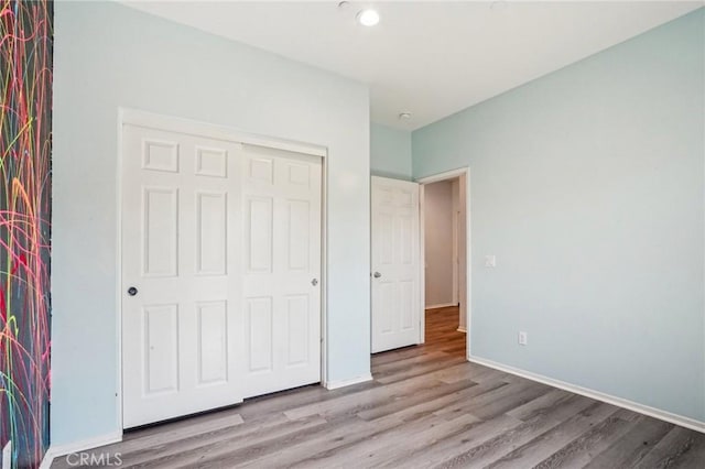 unfurnished bedroom with a closet, baseboards, and wood finished floors